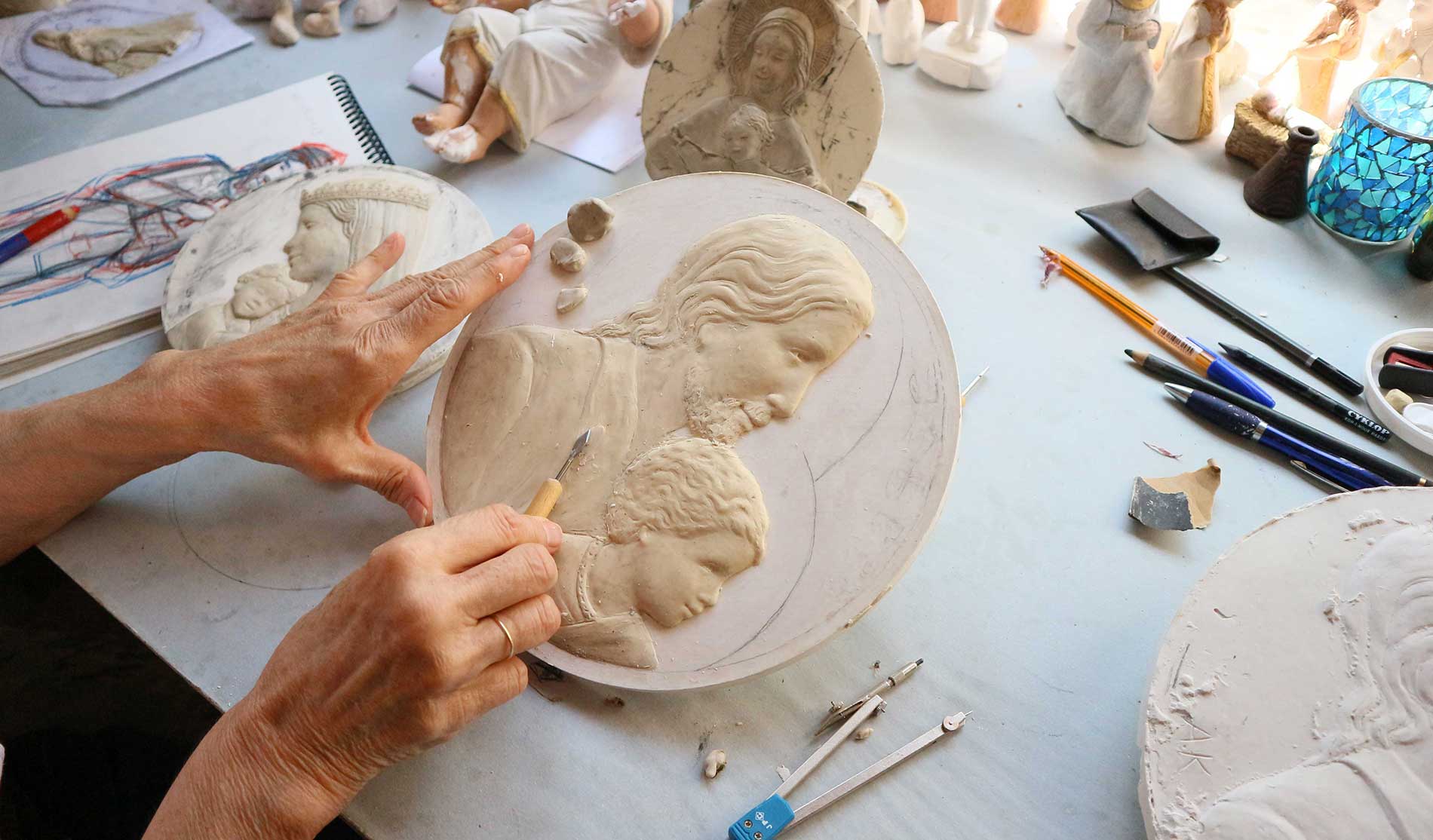 Artiste en train de créer un modèle de médaille de baptême en plastiline